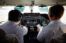 two pilots wearing bose headphones in the cockpit of an airplane